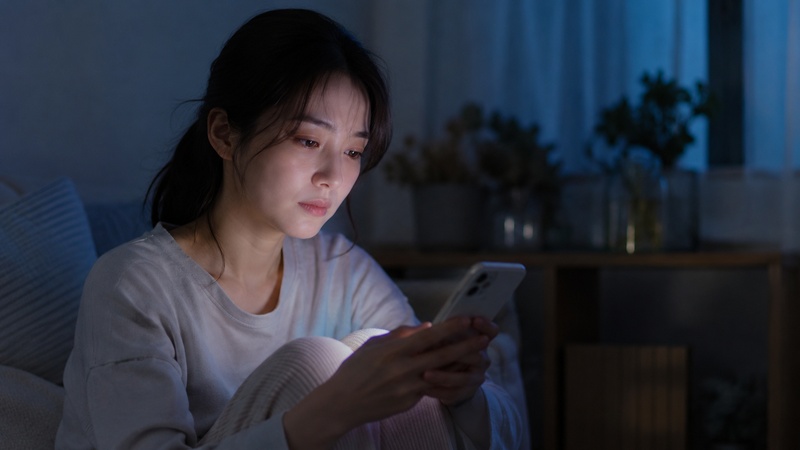 スマホを手に物思いにふける女性。人間関係に疲れたイメージ