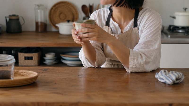 自宅のキッチンまわりで家事の合間にひと息つく主婦のイメージ