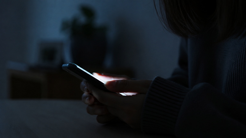 ひとりでスマホを見ながら悩む女性の手元のイメージ